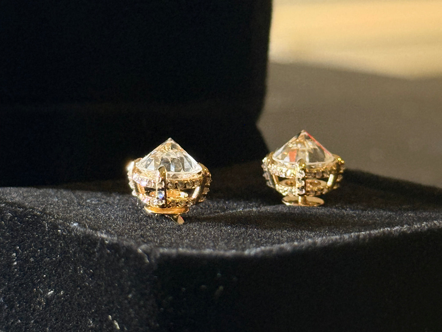 Gold and diamond earrings on a black surface